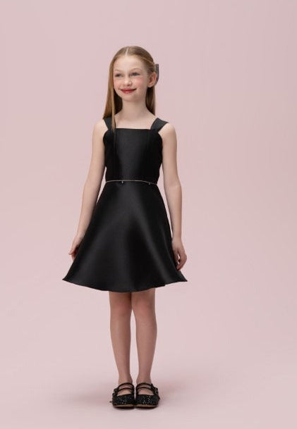 Menina com vestido infantil preto liso Petit Cherie, decote reto, alças largas e saia evasê.