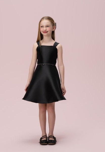 Menina com vestido infantil preto liso Petit Cherie, decote reto, alças largas e saia evasê.