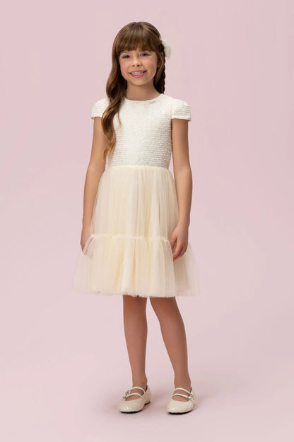 Menina com vestido infantil creme Petit Cherie, mangas curtas, corpo texturizado e saia em tule com camadas.