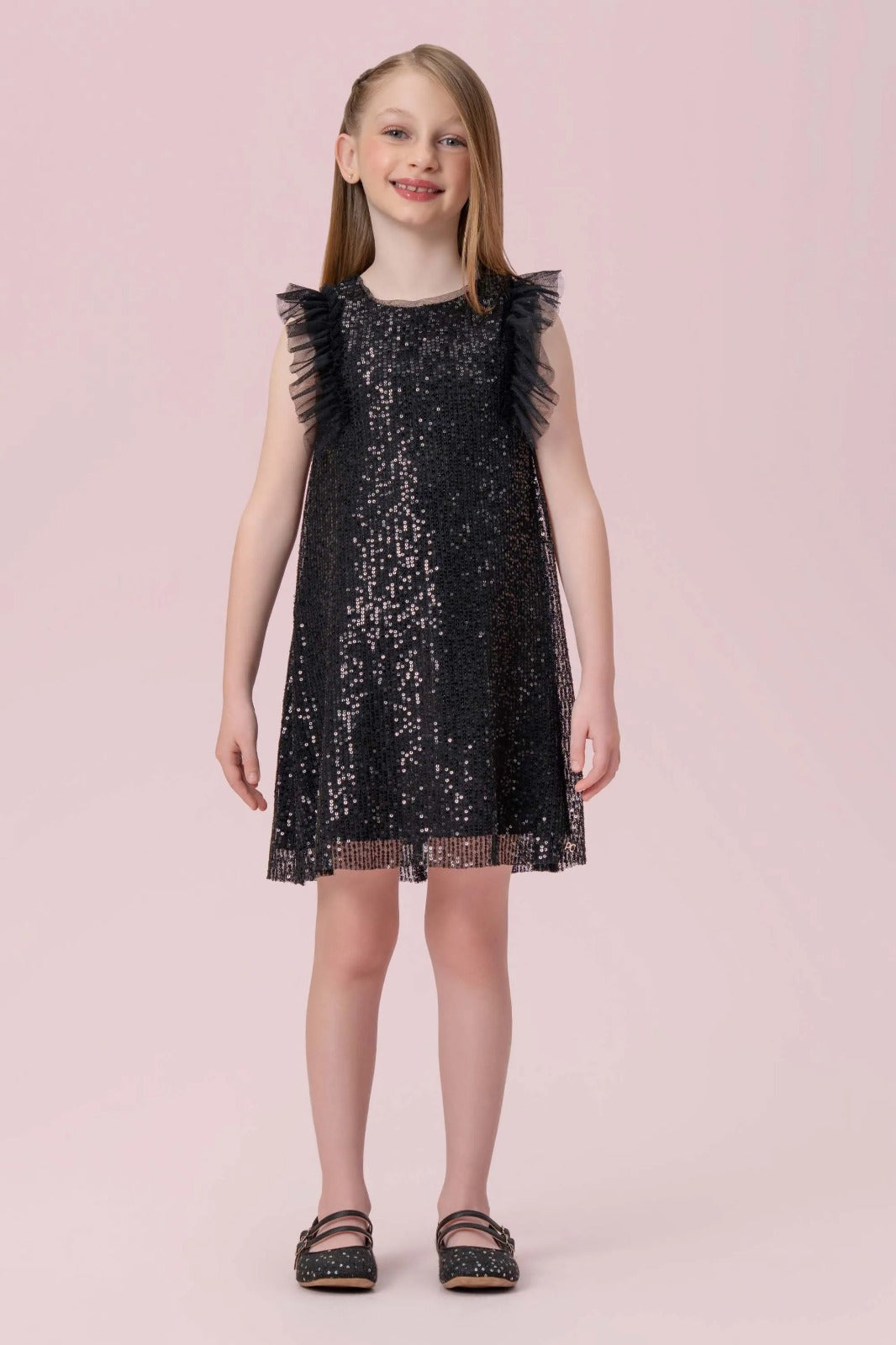Menina com vestido infantil preto de paetês Petit Cherie, modelagem soltinha e babados de tule nos ombros.