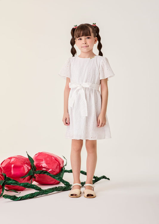 Menina usando vestido infantil Bimbi de laise off-white, com mangas curtas e laço na cintura, vista frontal.