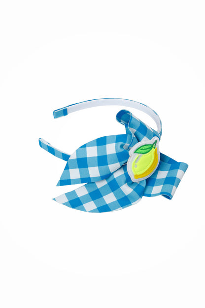 Tiara infantil Vichy Limão Siri com arquinho revestido em xadrez azul e branco, laço grande e aplique de limão amarelo.