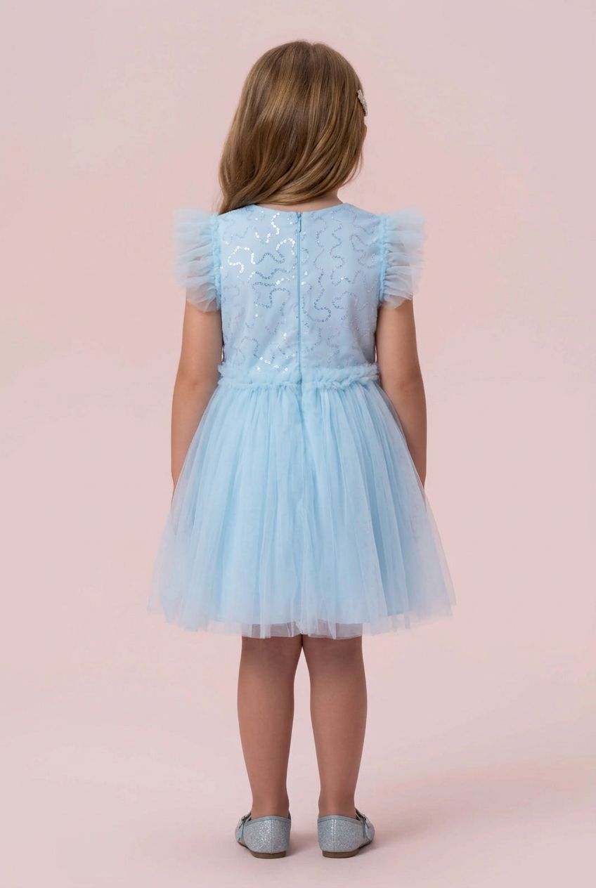 Menina de costas com o vestido azul-claro de paetês e tule, mostrando o zíper