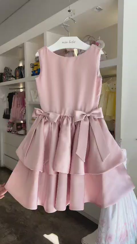 Vestido infantil de festa Buá em cetim rosê, sem mangas, com dois laços na cintura e saia rodada em duas camadas.
